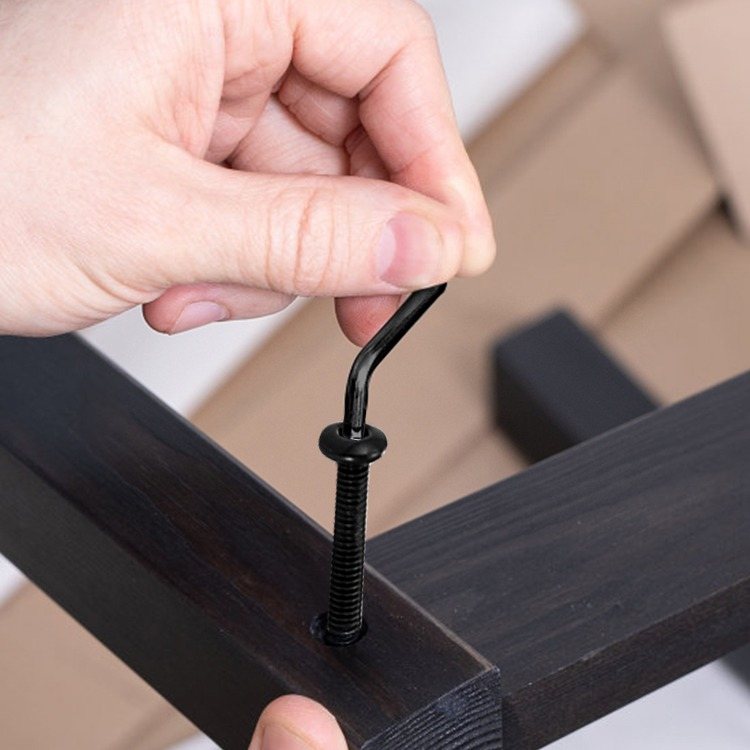 A screw eye being driven by hand into a wooden board